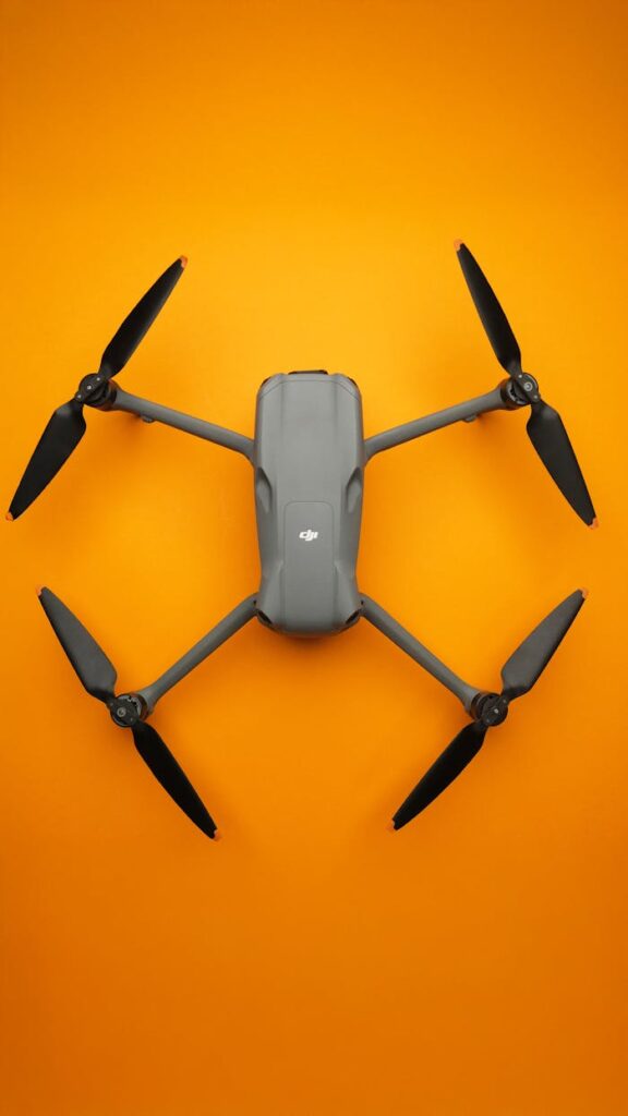 Crafting Captivating Headlines: Your awesome post title goes here Top view of a sleek folding drone isolated on a vibrant orange background.